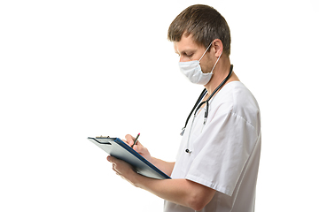 Image showing Male doctor writes in a clipboard with a ballpoint pen