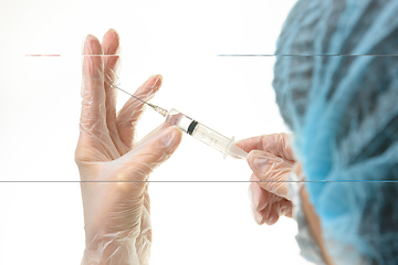 Image showing The doctor picks up the drug from the ampoule with a syringe, close-up