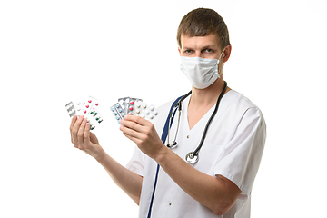 Image showing The doctor holds a variety of medications in his hands and joyfully looks into the frame