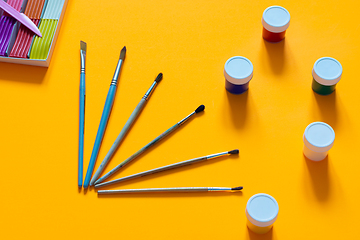 Image showing Brushes, gouache and plasticine are laid out on an orange table