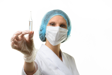 Image showing Girl doctor in a medical mask holds an ampoule with medicine in her hand