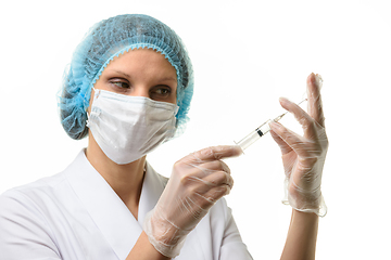 Image showing Nurse in mask and gloves draws medicine with a syringe from an ampoule