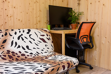 Image showing A fragment of the interior of a country house room, next to the sofa is a computer desk