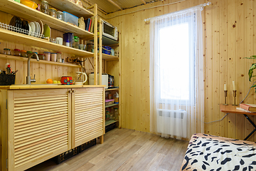 Image showing The interior of a small kitchen in a country cottage, the walls are decorated with wooden clapboard