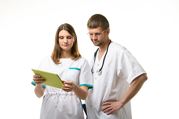 Image showing Doctor and nurse discussing the patient\'s tests, looking thoughtfully into the screen of a tablet computer