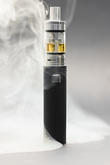 Image showing Electronic cigarette against background full of smoke