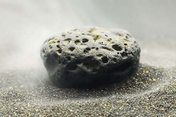 Image showing Smoke whirling around small meteorite stone