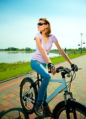 Image showing Young woman is sitting on her bicycle