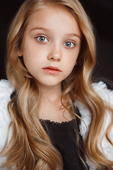 Image showing Little smiling girl posing in white outfit on black studio background