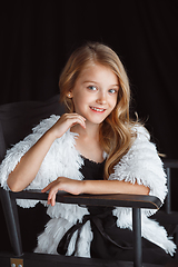 Image showing Little smiling girl posing in white outfit on black studio background