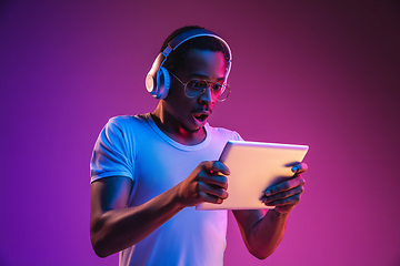 Image showing Young african-american man\'s listening to music in neon light