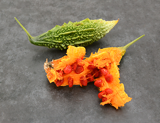 Image showing Green bitter gourd and overripe orange fruit, split apart