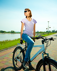 Image showing Young woman is sitting on her bicycle