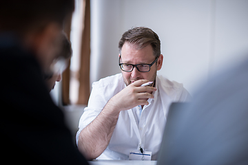 Image showing Business man writing notes while working on laptop