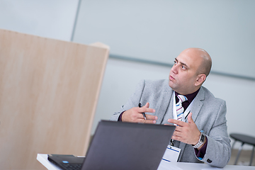 Image showing Business man writing notes while working on laptop