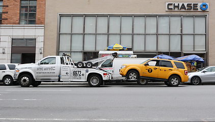 Image showing Broken down yellow taxi cab being towed away by a recovery vehic