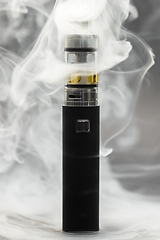 Image showing Electronic cigarette against background full of smoke