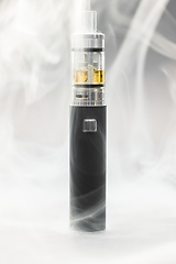 Image showing Electronic cigarette against background full of smoke