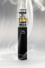 Image showing Electronic cigarette against background full of smoke