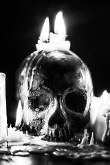 Image showing Candles and human skull in darkness closeup in black and whiter