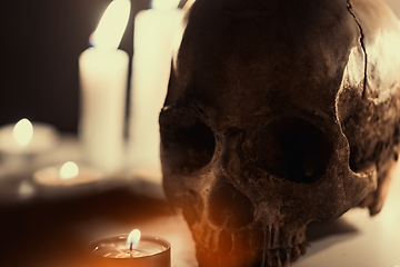 Image showing Human skull against dark background in candle light closeup