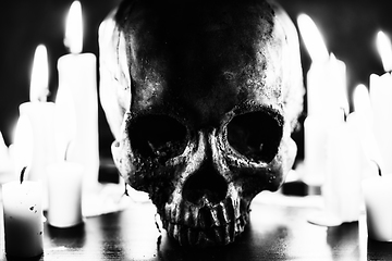 Image showing Candles and human skull in darkness closeup in black and whiter