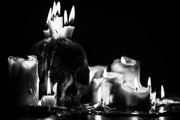 Image showing Candles and human skull in darkness closeup in black and whiter