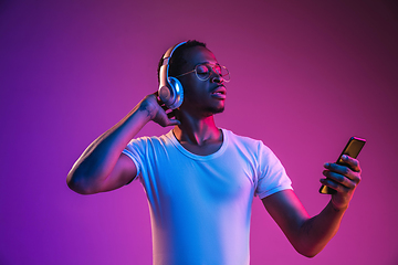 Image showing Young african-american man\'s listening to music in neon light