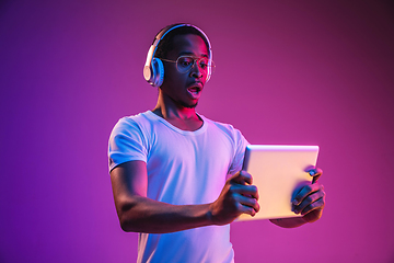 Image showing Young african-american man\'s listening to music in neon light