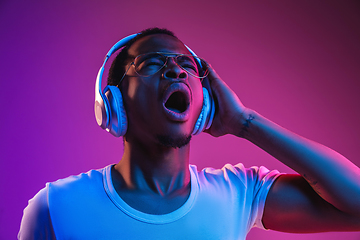 Image showing Young african-american man\'s listening to music in neon light