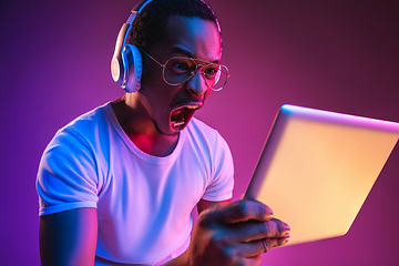 Image showing Young african-american man\'s listening to music in neon light