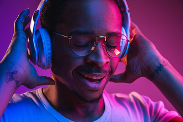 Image showing Young african-american man\'s listening to music in neon light