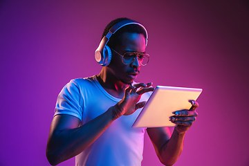 Image showing Young african-american man\'s listening to music in neon light