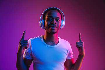 Image showing Young african-american man\'s listening to music in neon light