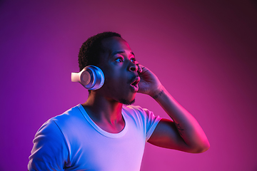 Image showing Young african-american man\'s listening to music in neon light