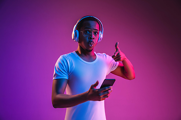 Image showing Young african-american man\'s listening to music in neon light