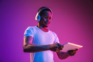 Image showing Young african-american man\'s listening to music in neon light