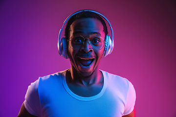 Image showing Young african-american man\'s listening to music in neon light