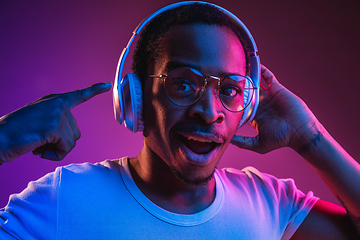 Image showing Young african-american man\'s listening to music in neon light