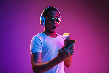 Image showing Young african-american man\'s listening to music in neon light