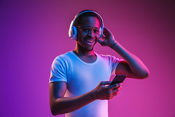 Image showing Young african-american man\'s listening to music in neon light