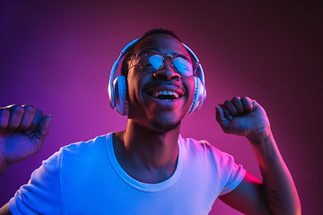 Image showing Young african-american man\'s listening to music in neon light