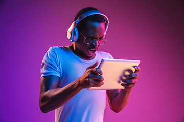 Image showing Young african-american man\'s listening to music in neon light