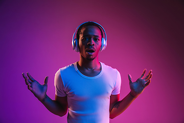 Image showing Young african-american man\'s listening to music in neon light