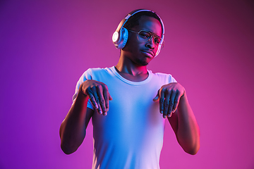 Image showing Young african-american man\'s listening to music in neon light