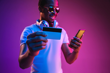 Image showing Young african-american man\'s listening to music in neon light