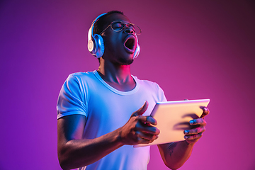 Image showing Young african-american man\'s listening to music in neon light