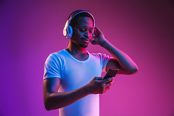 Image showing Young african-american man\'s listening to music in neon light