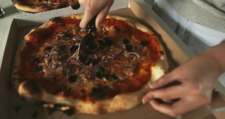 Image showing Delicious pizza being sliced up on the table