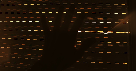 Image showing Hand reaching for sunlight behind shades